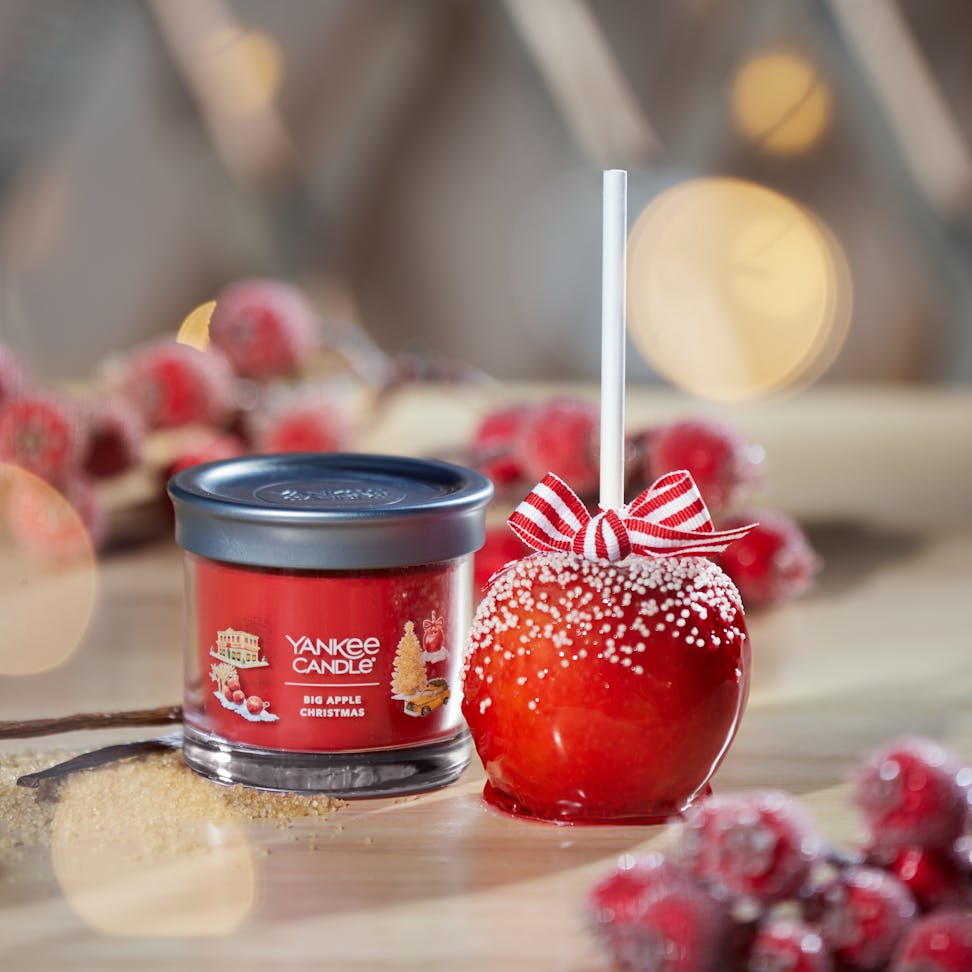 Passport to the Holidays Collection Big Apple Christmas Signature Small Tumbler Candle on a table next to a candy apple