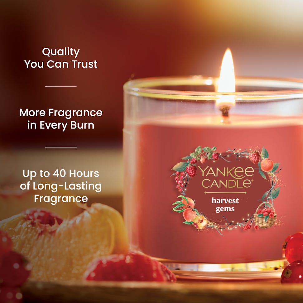 Red glass jar candle with fruit accents, promises up to 40 hours of long-lasting, quality fragrance burn time
