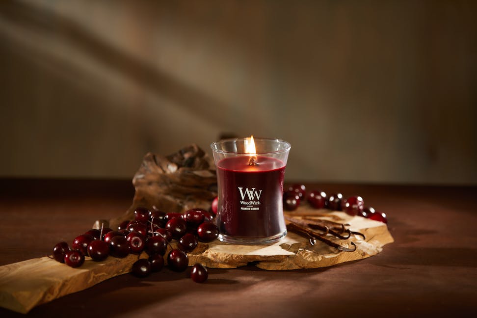 WoodWick Enchanted Destinations Collection Phantom Cherry Medium Hourglass Candle on a table with cherries