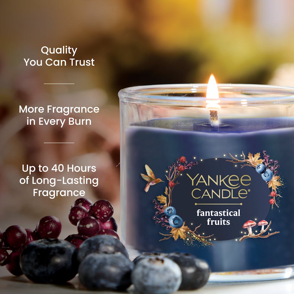 Blueberry scented candle in glass jar with fruit accents, text highlights long-lasting fragrance and quality.