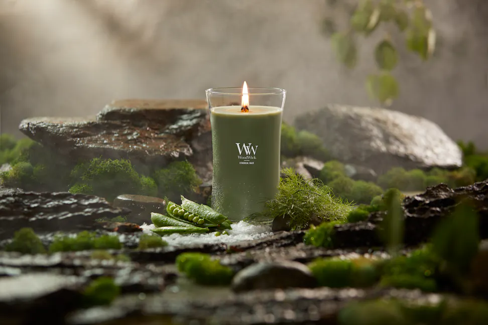 WoodWick Vapour Trails Collection Ethereal Haze Large Hourglass Candle surrounded by rocks, moss, salt, and snap peas