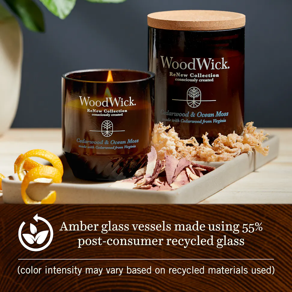 Two cedarwood and ocean moss woodwick renew candles on a tray with wood shavings and dried moss