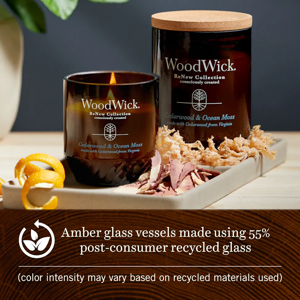 Two cedarwood and ocean moss woodwick renew candles on a tray with wood shavings and dried moss