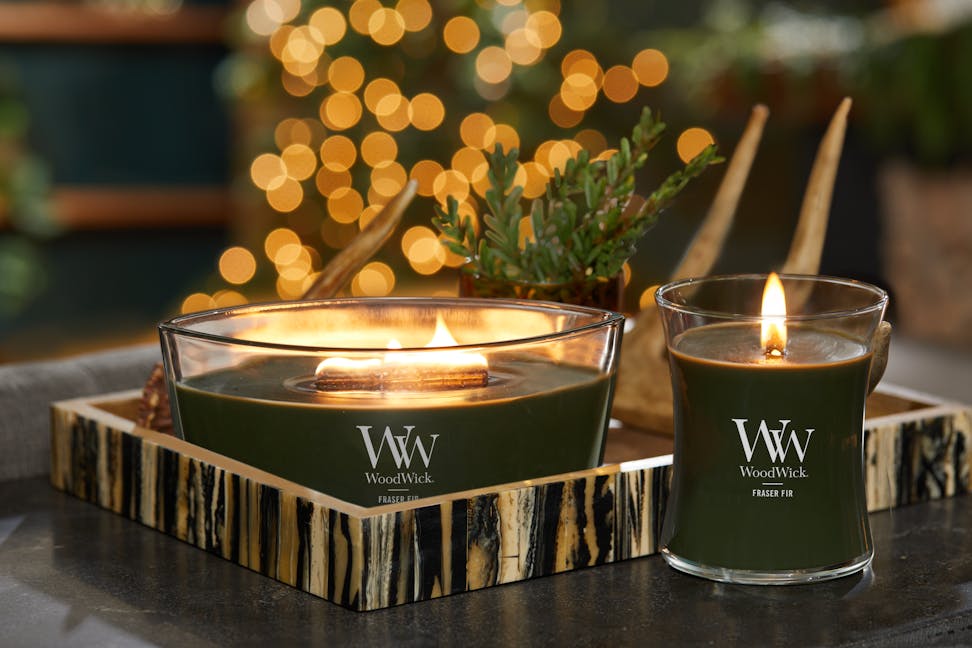 woodwick fraser fir ellipse candle and fraser fir medium hourglass candle on a table with tray, plant and antler