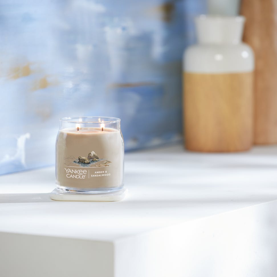 amber and sandalwood signature medium jar candle on table