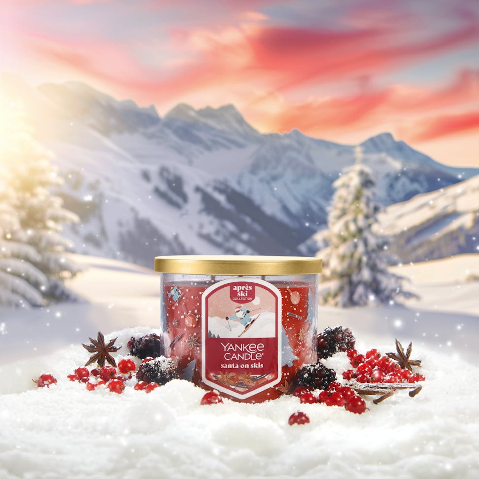 Apres Ski Collection Santa on Skis 3-Wick Candle in snow surrounded by berries and mountains