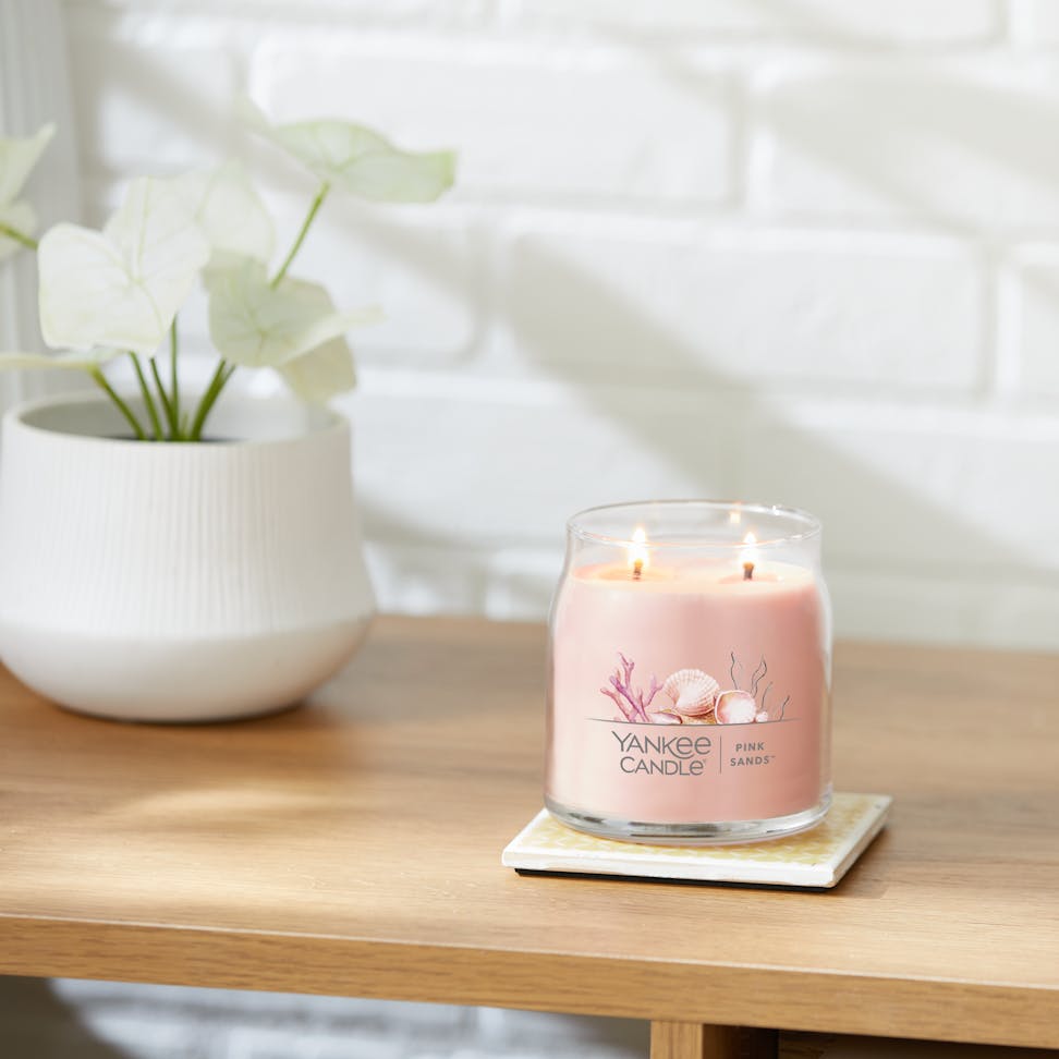 pink sands signature medium jar candle lit on side table