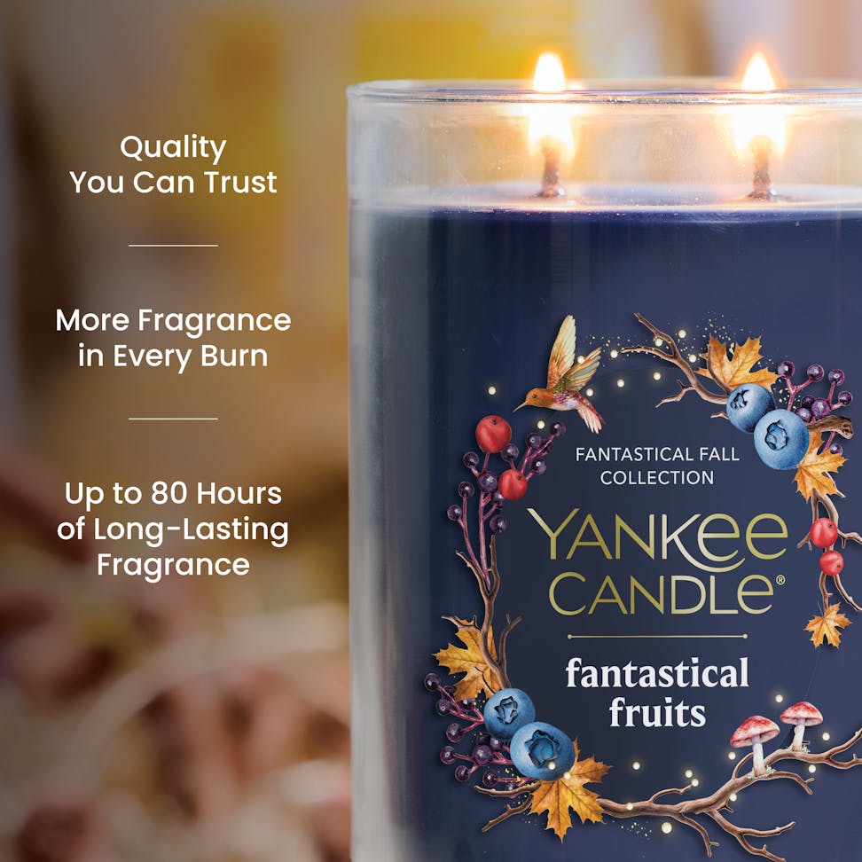 Large blue scented candle in glass jar with autumn fruit design, text highlights long-lasting fragrance benefits