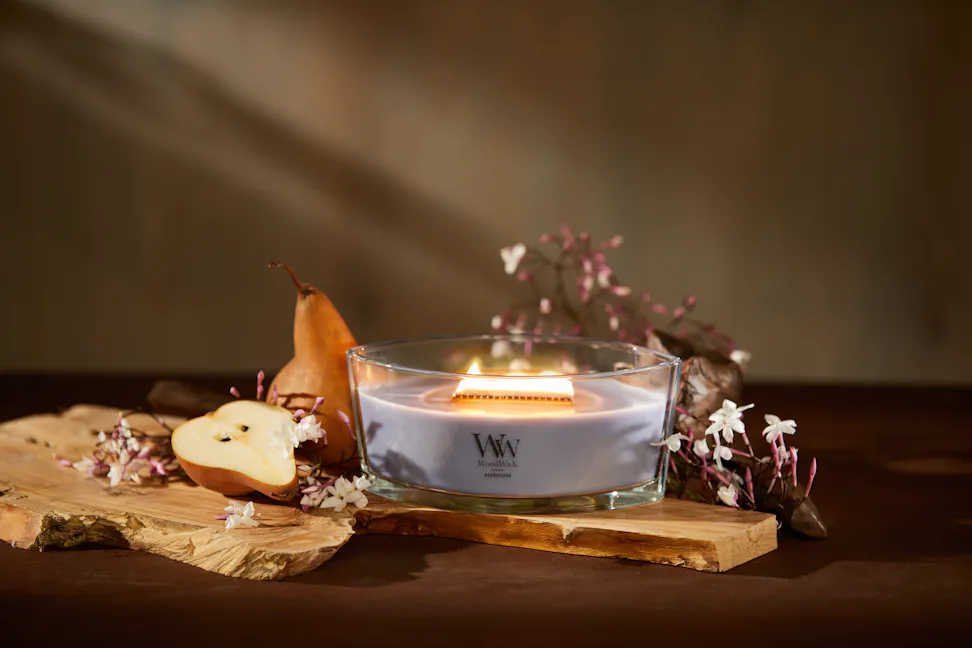 WoodWick Enchanted Destinations Collection Hypnoflora Ellipse Candle on a table with flowers and pears