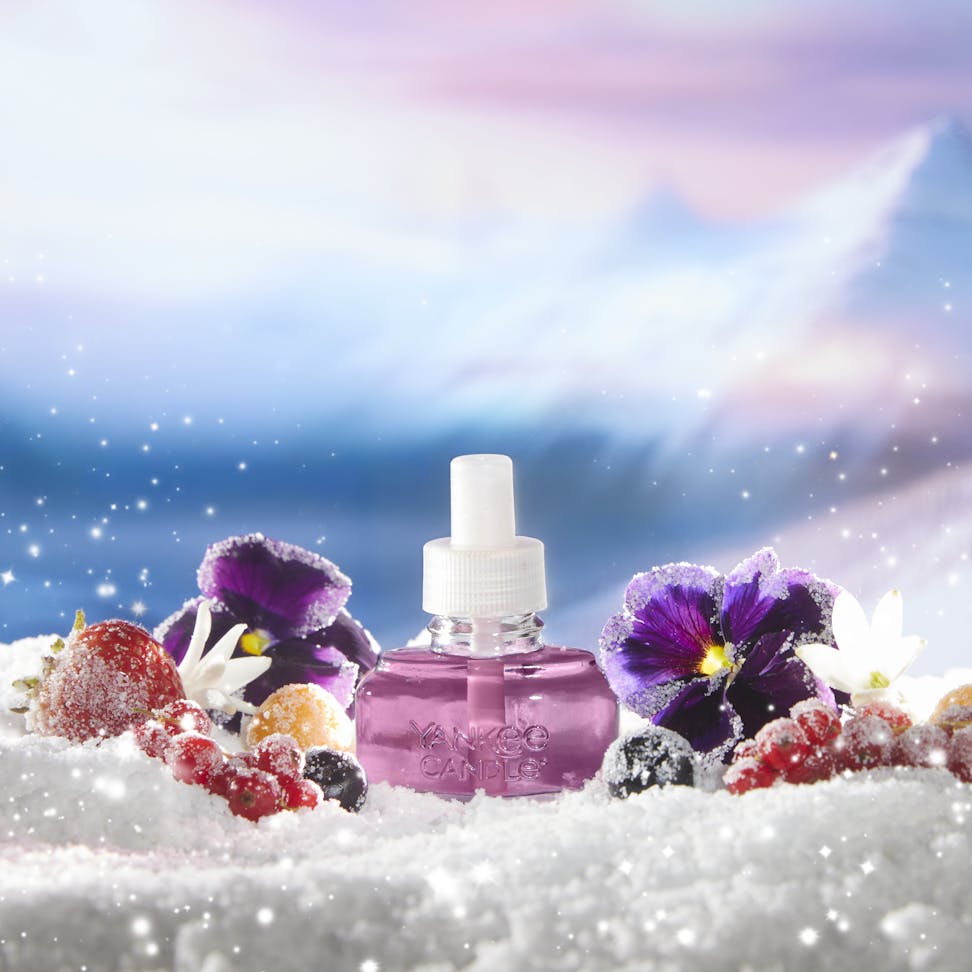 purple scentplug refill on snowy surface with flowers and berries and with mountains in distance