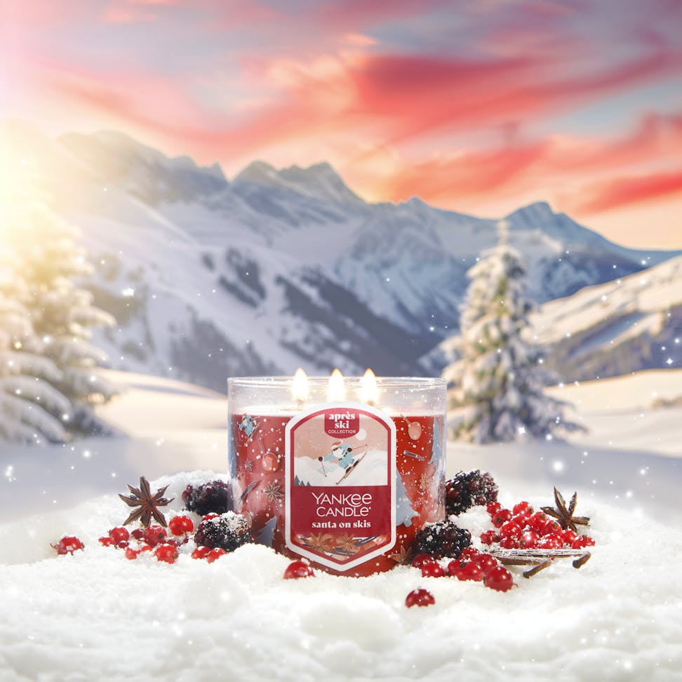 Apres Ski Collection Santa on Skis 3-Wick Candle in snow surrounded by berries, spices, and mountains