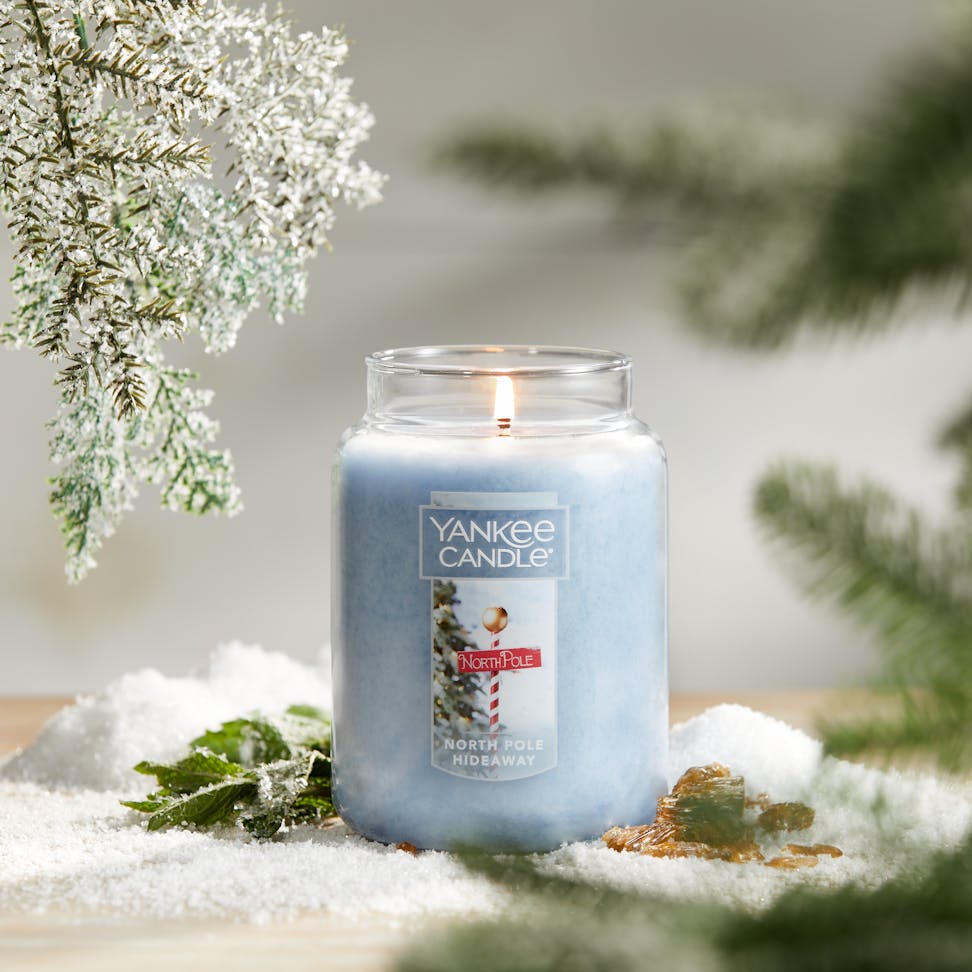 Passport to the Holidays Collection North Pole Hideaway Original Large Jar Candle on a table surrounded by decorative snow