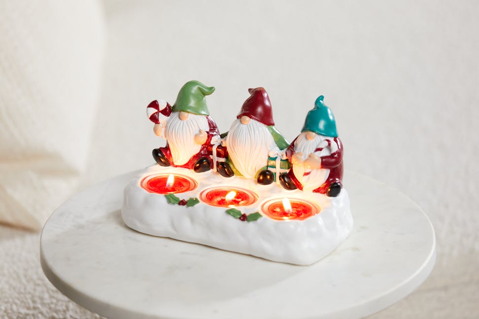 gnome presents tea light candle holder with three lit tea light candles on a white table