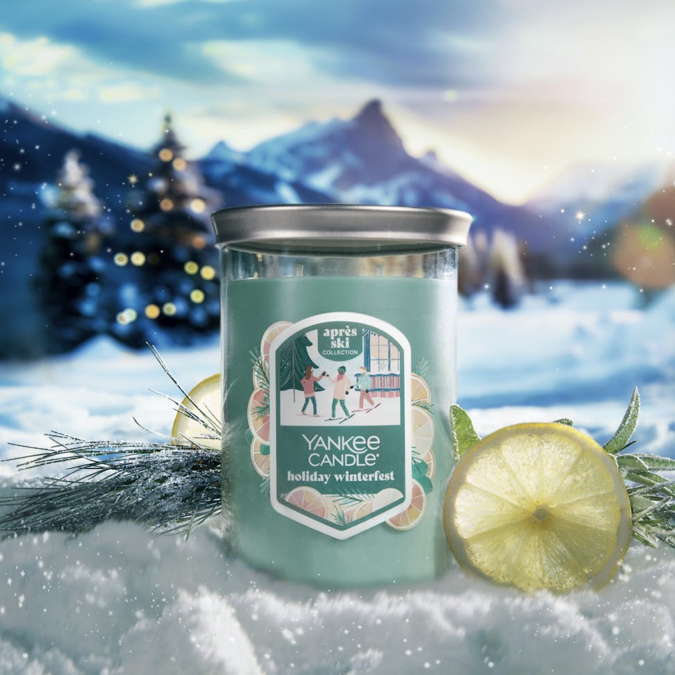 Apres Ski Collection Holiday Winterfest Signature Large Tumbler Candle in snow surrounded by lemon slices, branches, and mountains