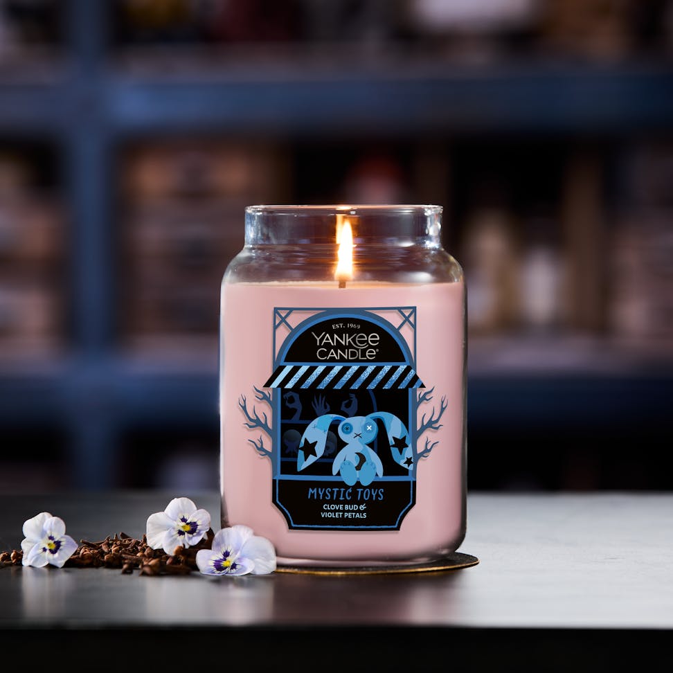 Large pink scented candle in glass jar burning with floral accents, cozy home decor, relaxing aromatherapy atmosphere