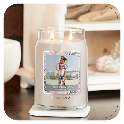 a cream-colored signature large jar candle with a personalized photo label of a woman and a young girl with messaging saying let the good times roll and love you so much on a table