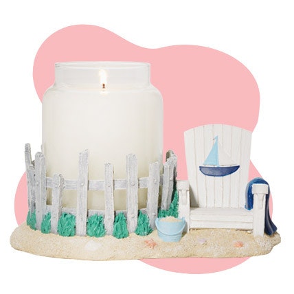a white original large jar candle in a sailboat beach chair jar candle holder in a pink background