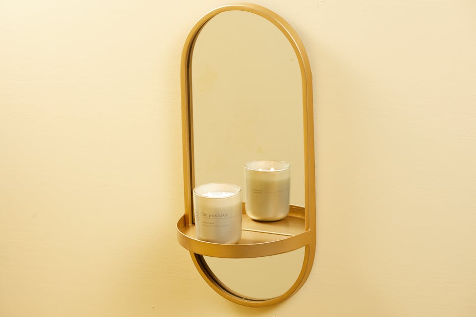 chesapeake bay candle intentions collection be positive citrus sugar medium two wick jar candle on a gold mirror hanging on a wall