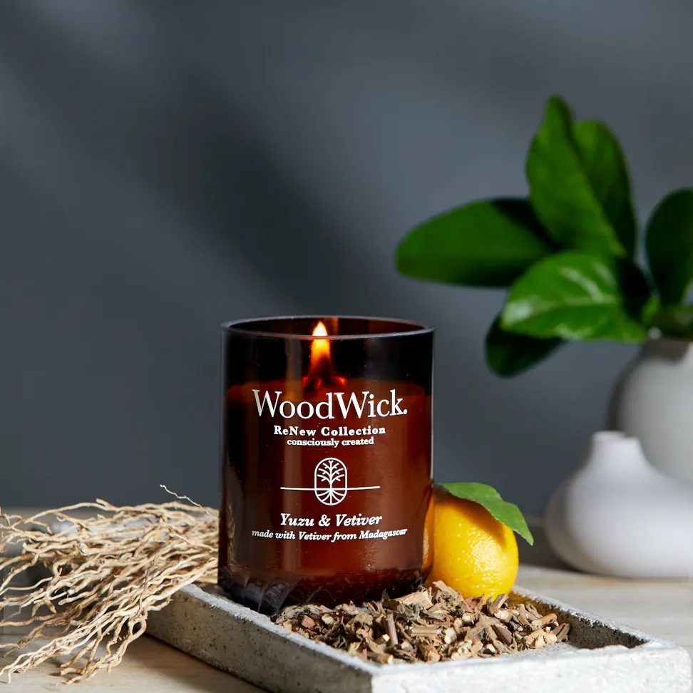 WoodWick ReNew Collection Yuzu & Vetiver Large Candle next to a lemon on a table