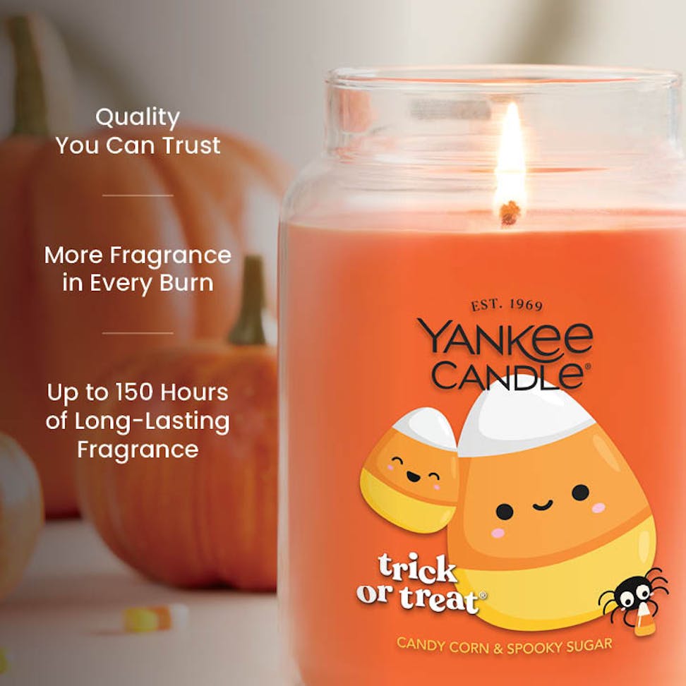Large orange scented candle with candy corn design, long-lasting home fragrance, festive Halloween decor.