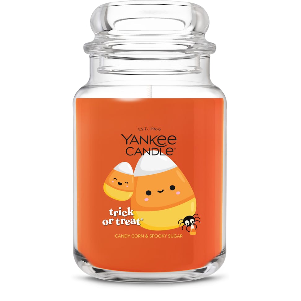 Large orange jar candle with cute candy corn and spider design, festive Halloween decor, trick or treat label