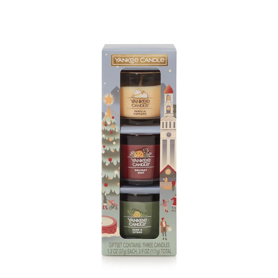 Gift set with three scented candles in a holiday-themed box, including vanilla, balsam, and berry scents.