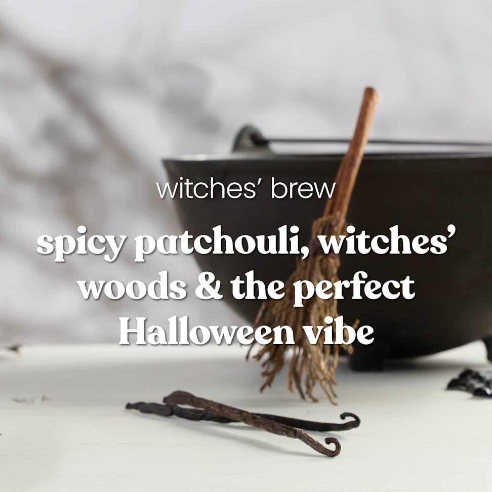 Large cauldron with rustic broom, Halloween decor, and text about spicy patchouli and witchesâ€™ woods fragrance.