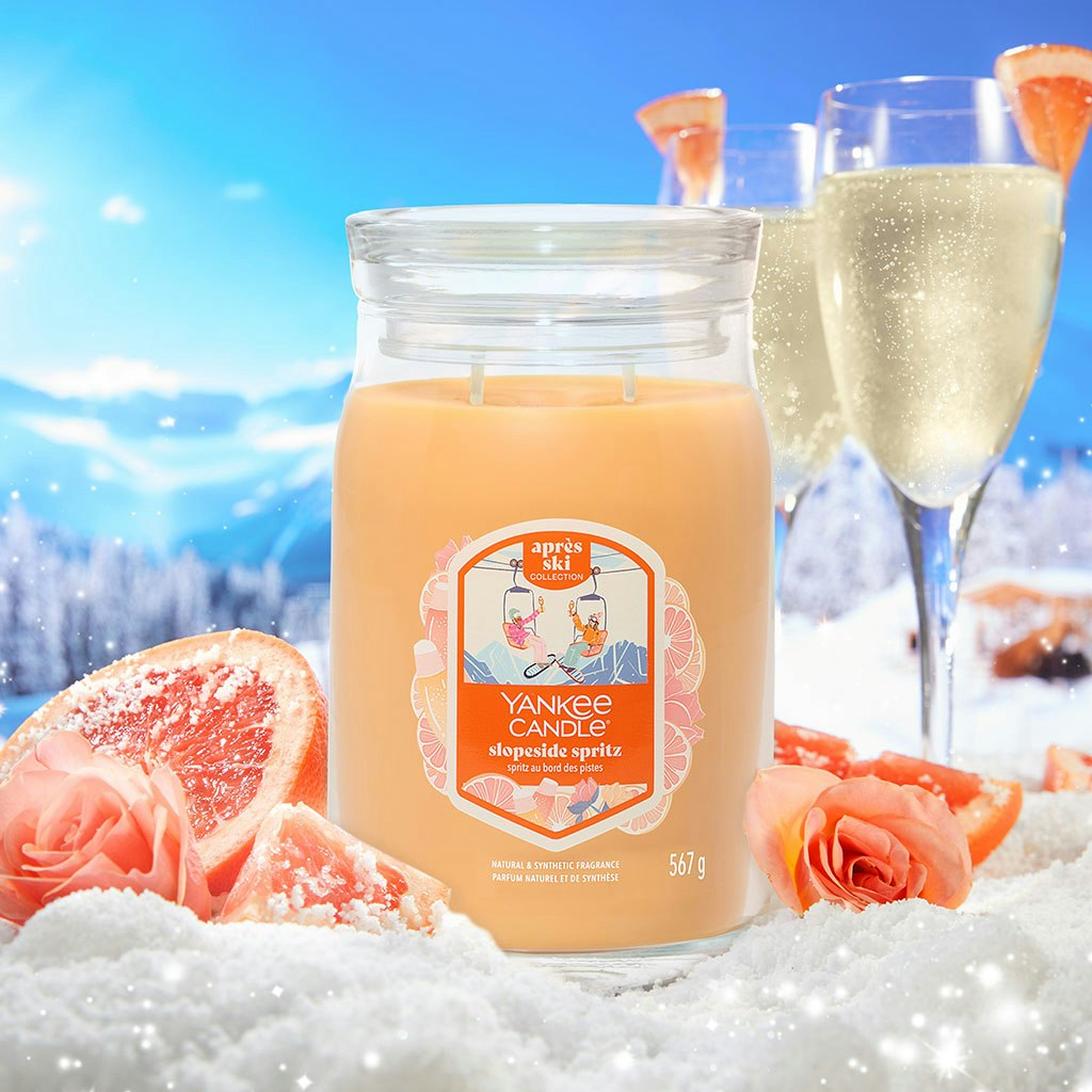 Large peach-colored soy wax candle in glass jar with grapefruit, snow, and champagne for home decor ambiance
