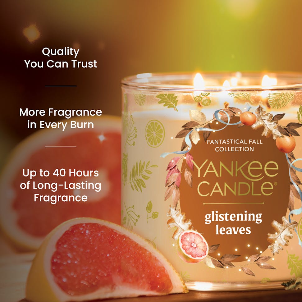 Scented candle with glowing flame, festive fall design, long-lasting fragrance, grapefruit accent, quality text nearby
