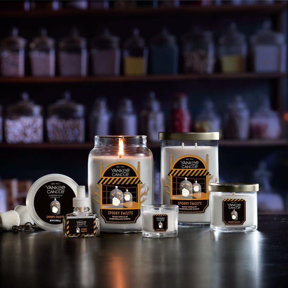 Large Halloween-themed scented candle with festive label, surrounded by matching home fragrance products on a shelf.