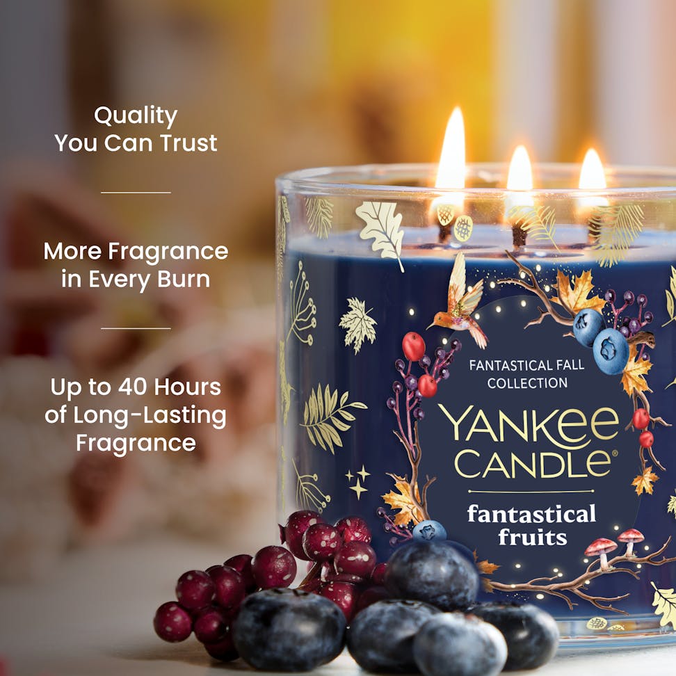 Large decorative candle with three flames, surrounded by berries, with text highlighting long-lasting fragrance.
