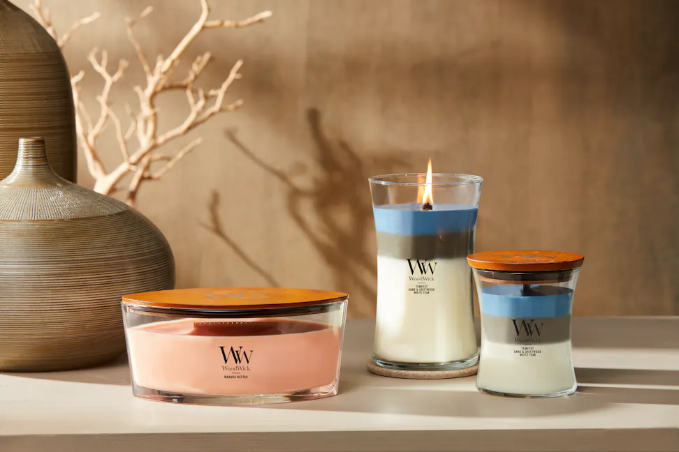 three woodwick candles with brown vases and branches