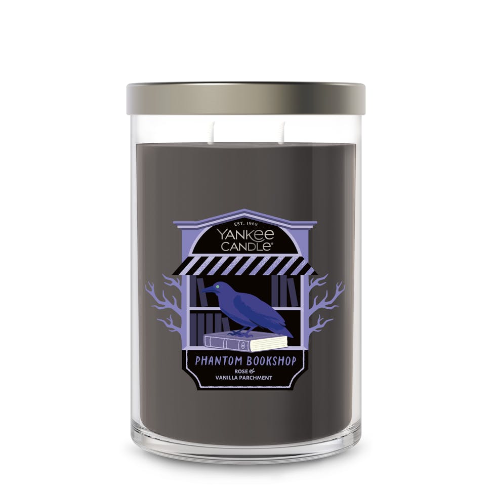 Large black scented candle in glass jar with label featuring raven and bookshop, perfect for home decor