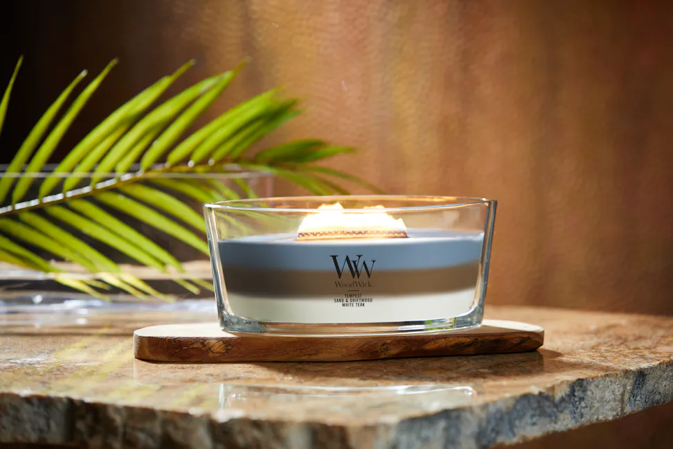 woodwick trilogy ellipse candle on wood slab and stone table with leaf frond in glass bowl