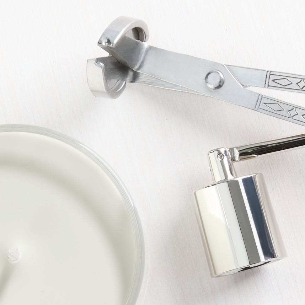 Luxury candle with silver wick trimmer and snuffer, perfect for home decor and aromatherapy relaxation.