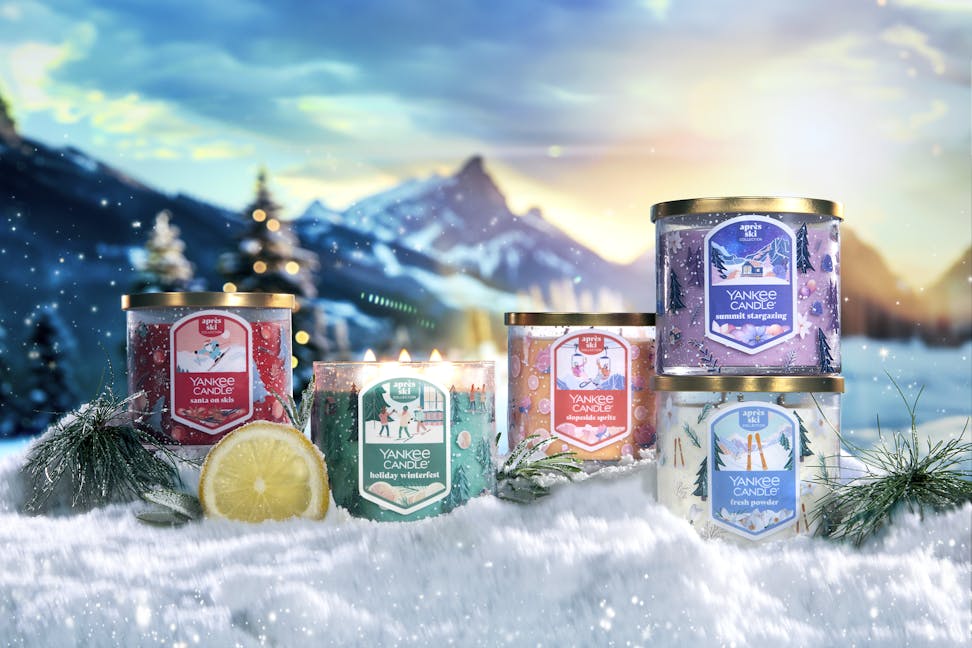Apres Ski Collection Santa on Skis 3-Wick Candle, Holiday Winterfest 3-Wick Candle, Slopeside Spritz 3-Wick Candle, Summit Stargazing 3-Wick Candle, and Fresh Powder 3-Wick Candle in snow surrounded by mountains, slices of lemon, and branches